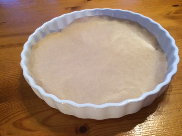 Lining a flan dish with greaseproof paper.