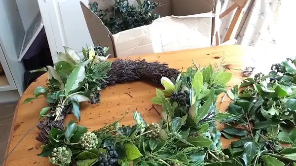 Securing bundles of foliage to a wreath base in two directions.