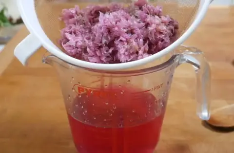 Straining chive vinegar through a sieve.